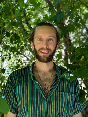 Portrait d'Arnaud Paul en extérieur, devant un feuillage