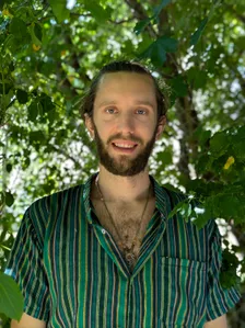 Portrait d'Arnaud Paul en extérieur, devant un feuillage
